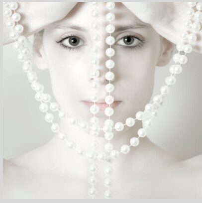 Woman with pearls hanging over her face